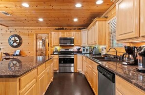 A kitchen with wooden cabinets, a microwave, an oven, and a dishwasher. - S'mores at Sunset-Luxury 3-bedroom cabin located in the heart of Broken Bow. (Broken Bow)