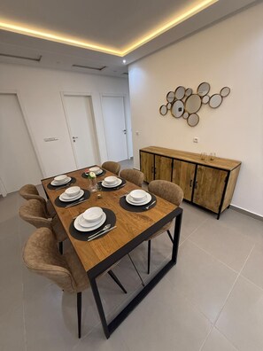 A dining area with a wooden table set for four, surrounded by cushioned chairs. - Palm House Tanger Apartment 02 (Tanger)