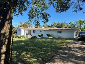 A single-story house with a front porch, a driveway, and a parked car. - Spacious Home - 10 minutes to Downtown (Nashville)
