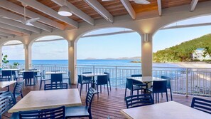 An outdoor dining area with tables and chairs, overlooking a beach and the sea. - Studio at Limetree Beach Resort by Club Wyndham on Beautiful St. Thomas (Southside)