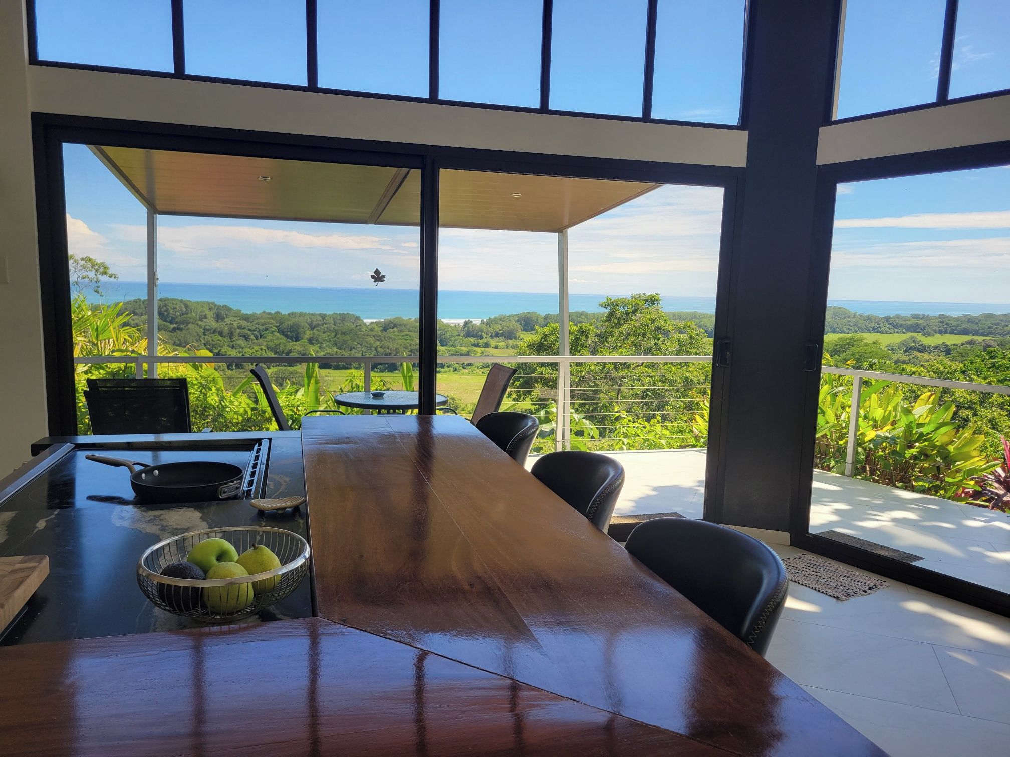 A dining area with a view of a lush landscape and the ocean.