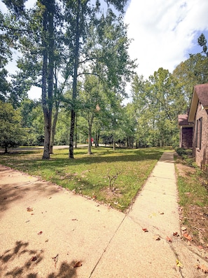 A pathway leading to a building with a brick facade, surrounded by trees and grass. - Home in Golf Course Community- minutes from everything (Oxford)