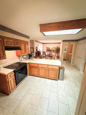 A kitchen with wooden cabinets, a black stove, and a tiled floor. - Home in Golf Course Community- minutes from everything (Oxford)