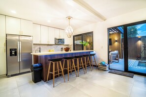 Eine moderne Küche mit integriertem Mikrowellenherd, einem Edelstahlkühlschrank und einer Bar mit Hockern.