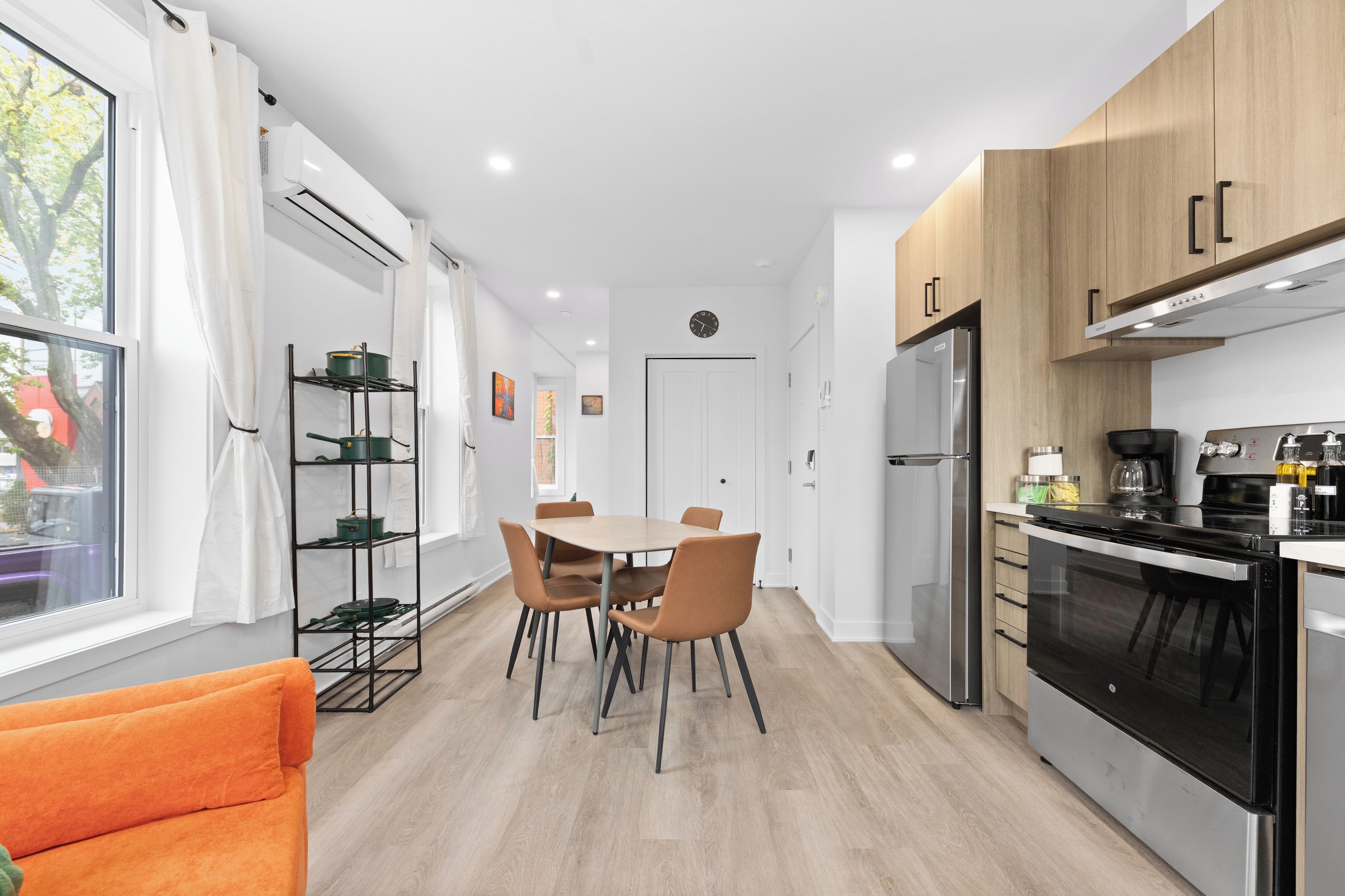 Eine moderne Küche mit Essbereich, Holzschränken und einem schwarzen Kühlschrank.