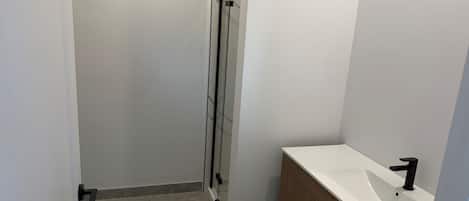 Ein Badezimmer mit Dusche, Waschbecken und Holzschränken.