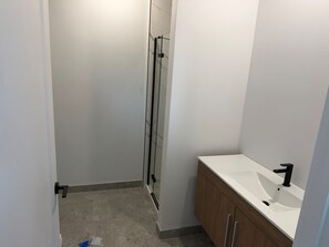 Un baño con ducha, lavamanos y armarios de madera.