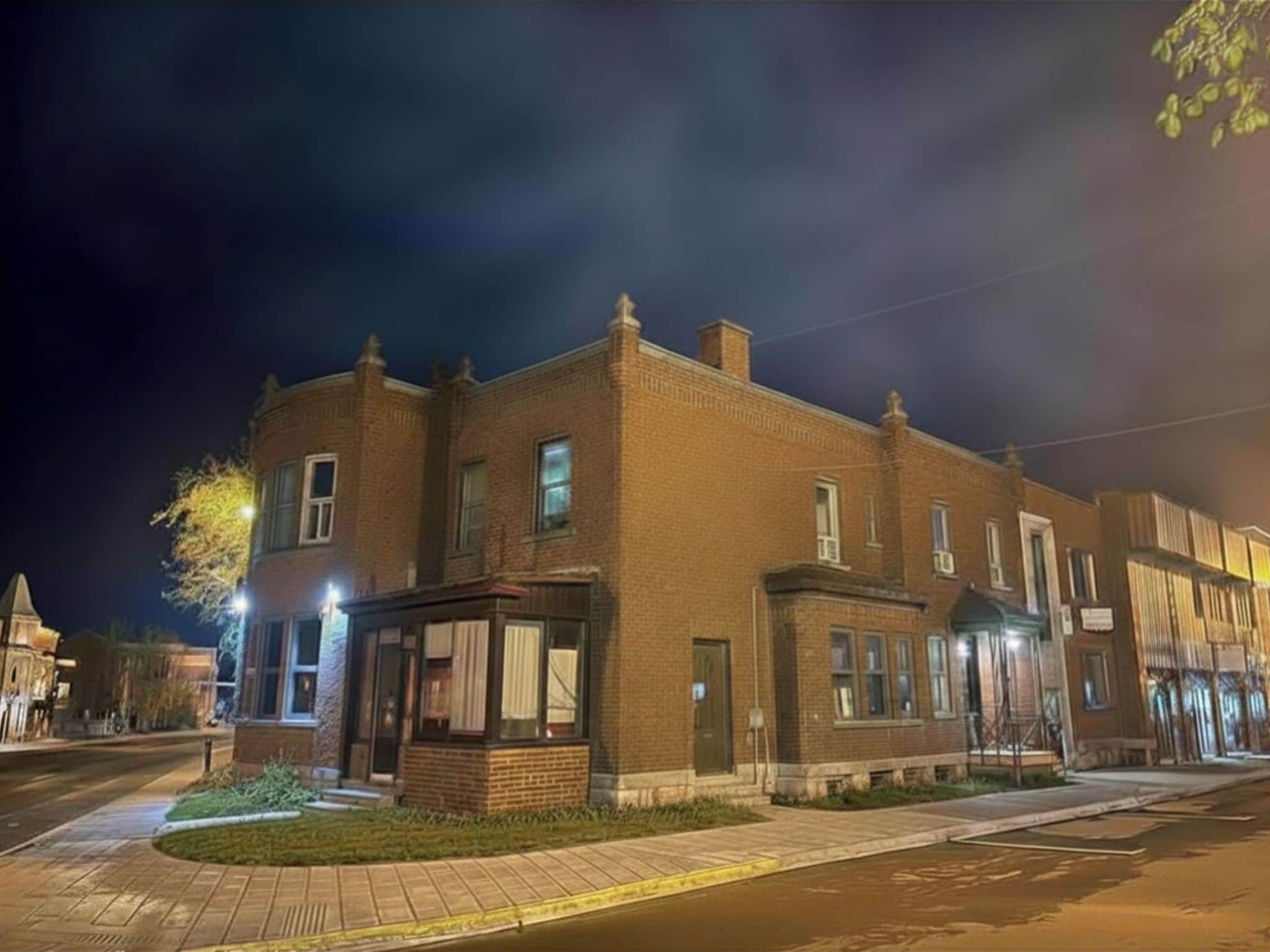 A two-story brick building with a corner entrance and a small porch.