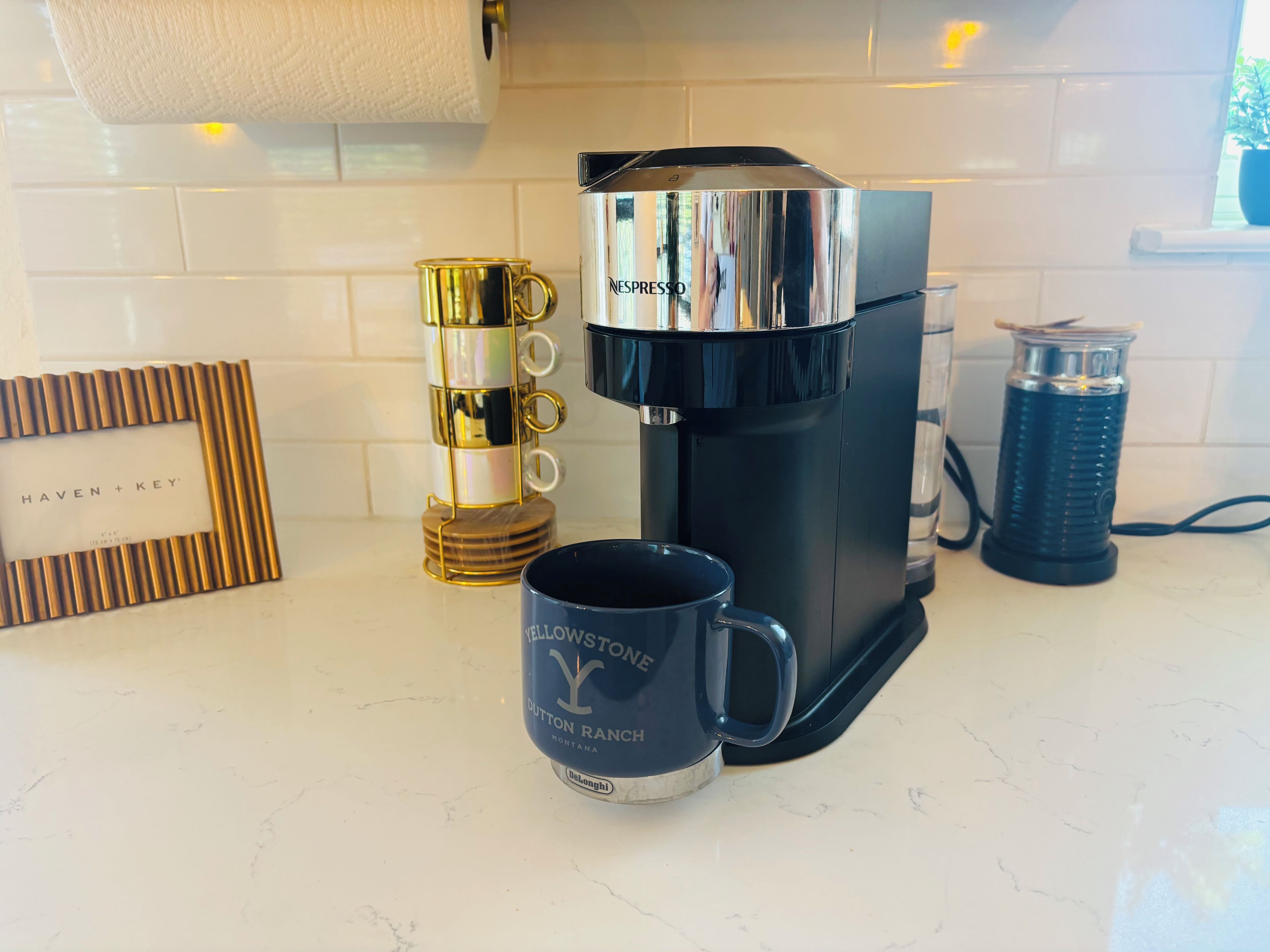Une machine à café, une pile de tasses et une tasse sur un plan de travail de cuisine.