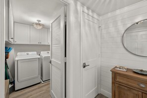 A laundry room with two washing machines, a dryer, and a ceiling light fixture.