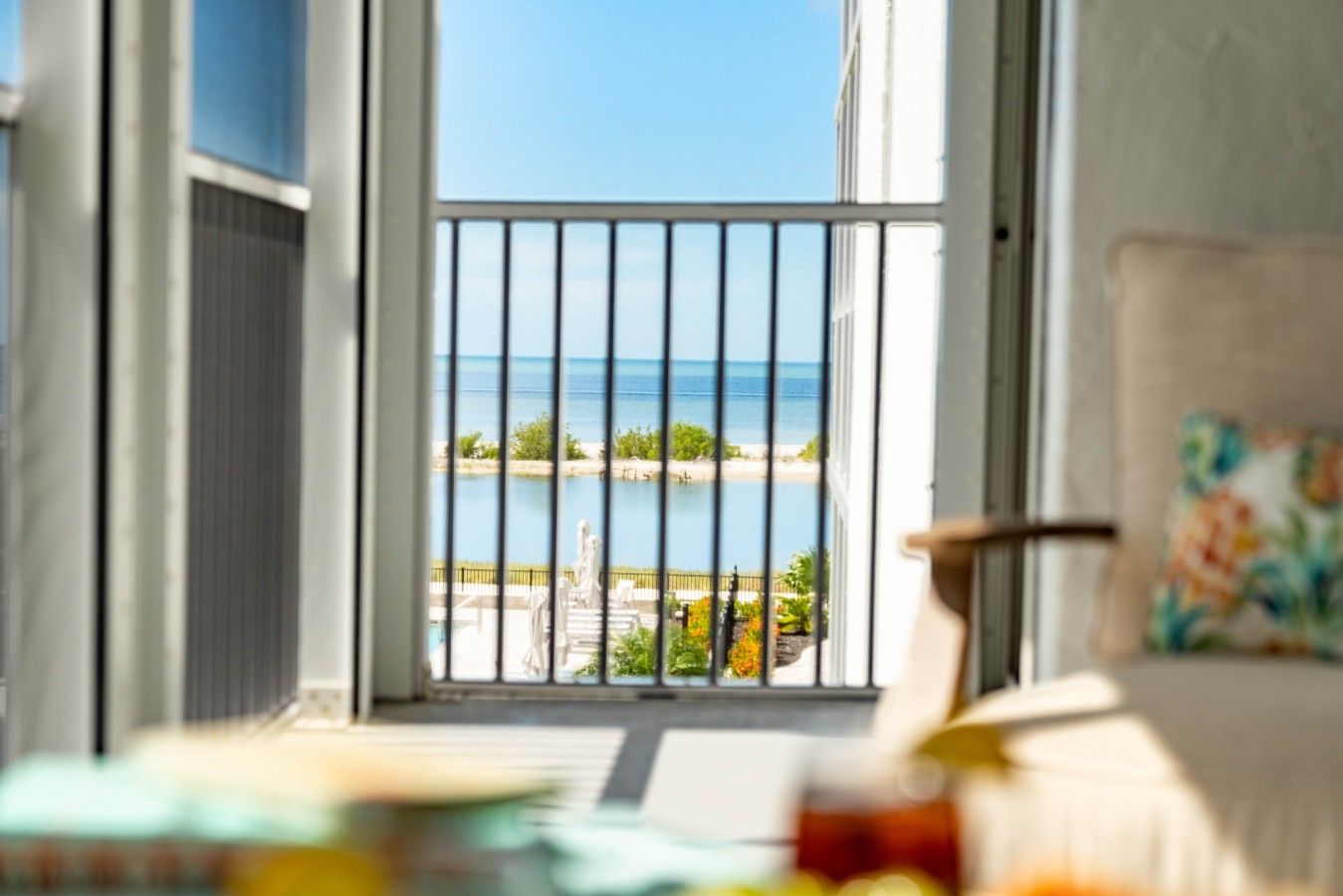 Un balcón con vista al mar y una silla con cojín floral.