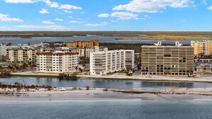 Uma área residencial costeira com vários edifícios altos, uma praia de areia e uma faixa de água calma.