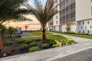 A modern building with a courtyard, palm trees, and a clear sky.