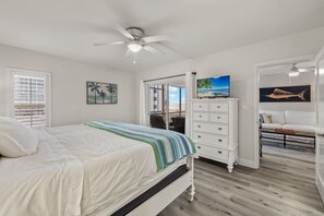 Ein Schlafzimmer mit Bett, Kommode, Fernseher und Blick auf den Strand.