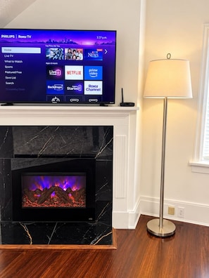 A television on a wall-mounted stand displaying a Roku TV interface with various streaming options.