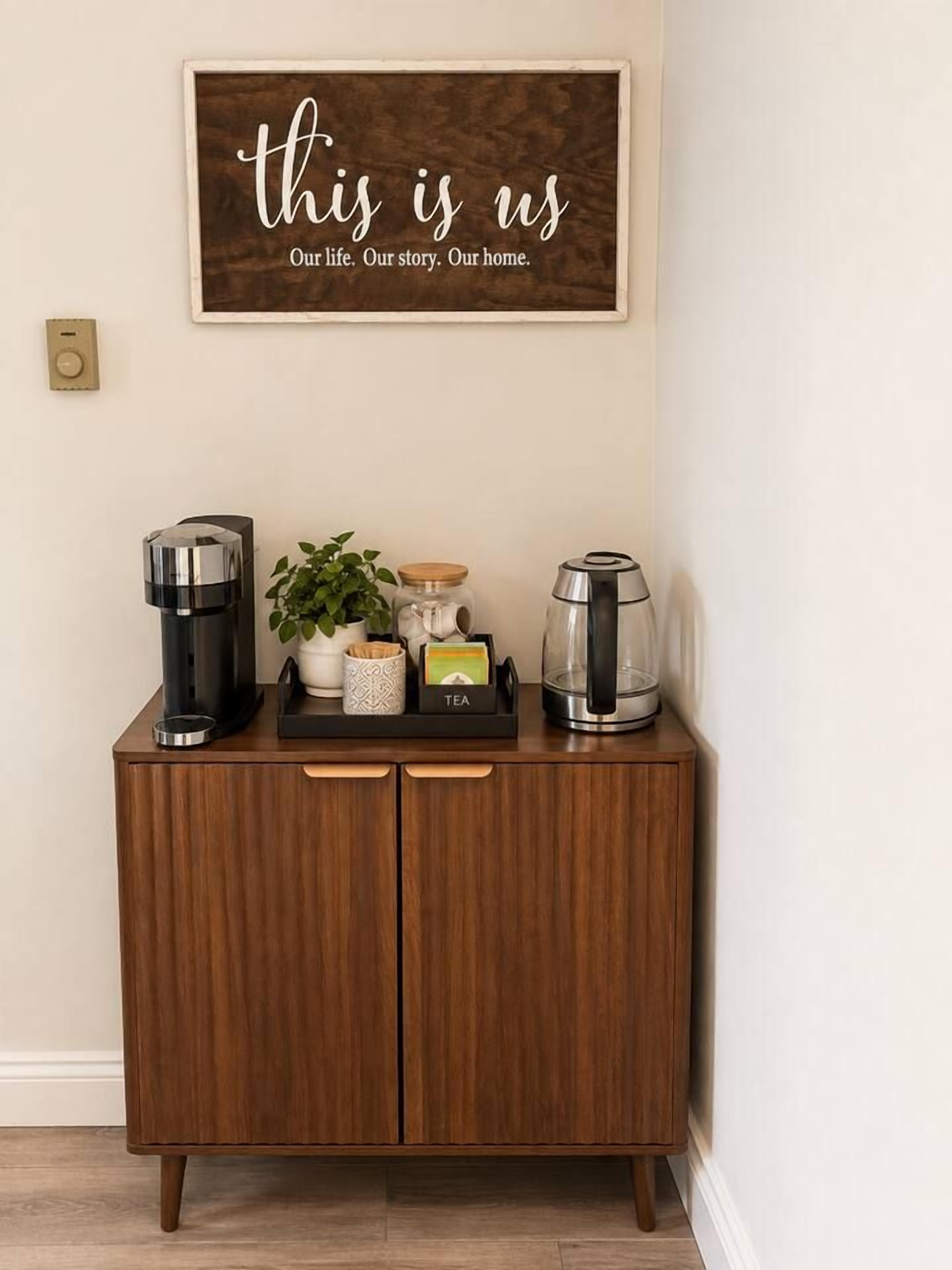 A wooden cabinet with a coffee maker, a plant, and a kettle on top.