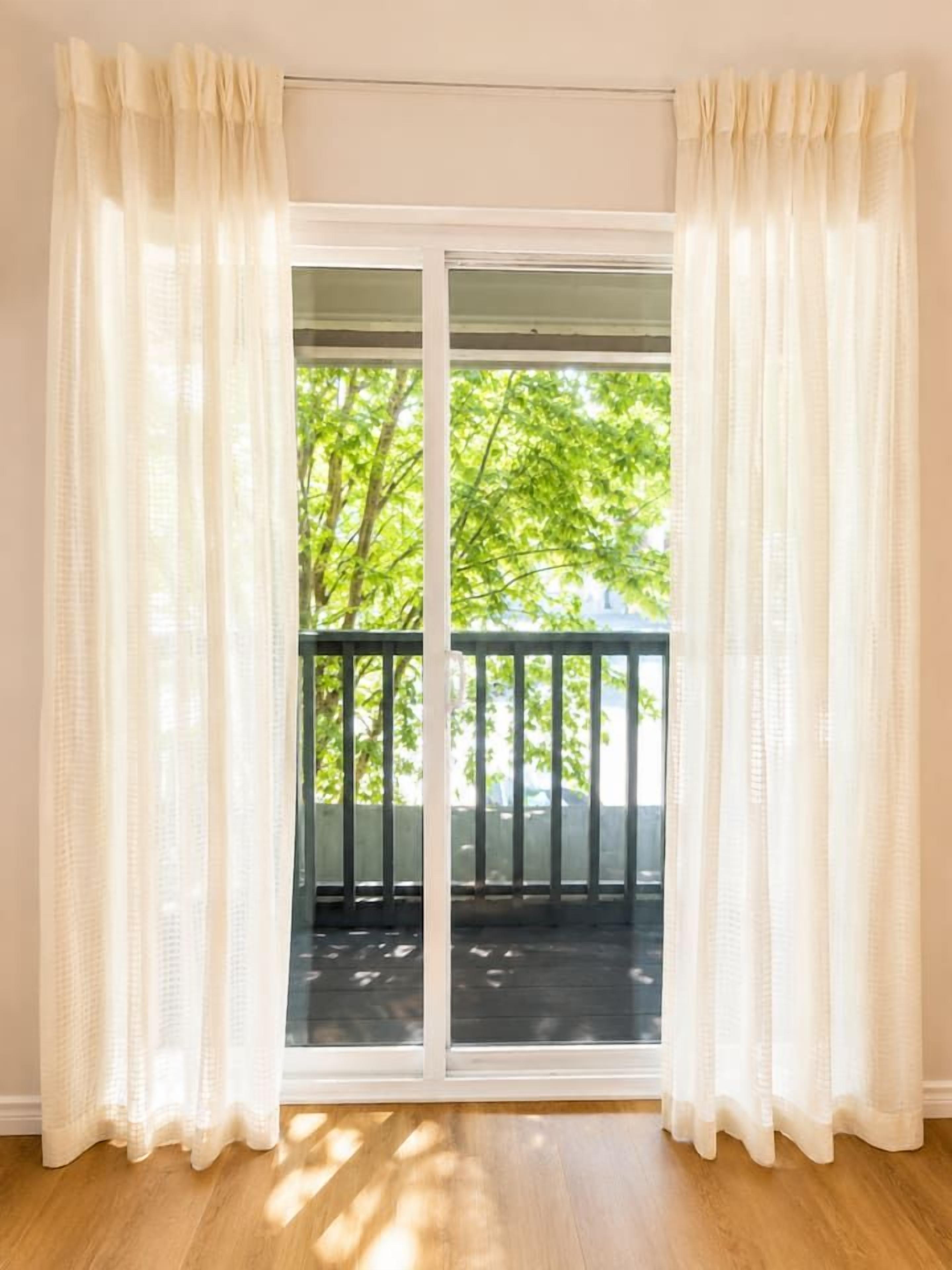 Et værelse med en skydedør, der fører ud til en balkon med gelænder af træ.