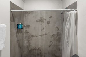 A shower with a curtain, a towel rack, and a bottle of shampoo. - Casa Magnolia Apt 10 | Studio Apt in Santurce (San Juan de Puerto Rico)