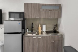 Eine kompakte Küche mit Kühlschrank, Mikrowelle, Spüle und Herd.