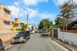Eine Wohnstraße mit parkenden Autos, Häusern und blauem Himmel.