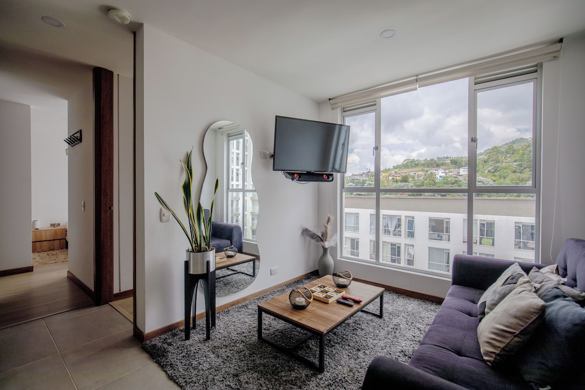 Una sala de estar moderna con un ventanal grande, un televisor de pantalla plana, un sofá, una mesa de centro y una planta en maceta.