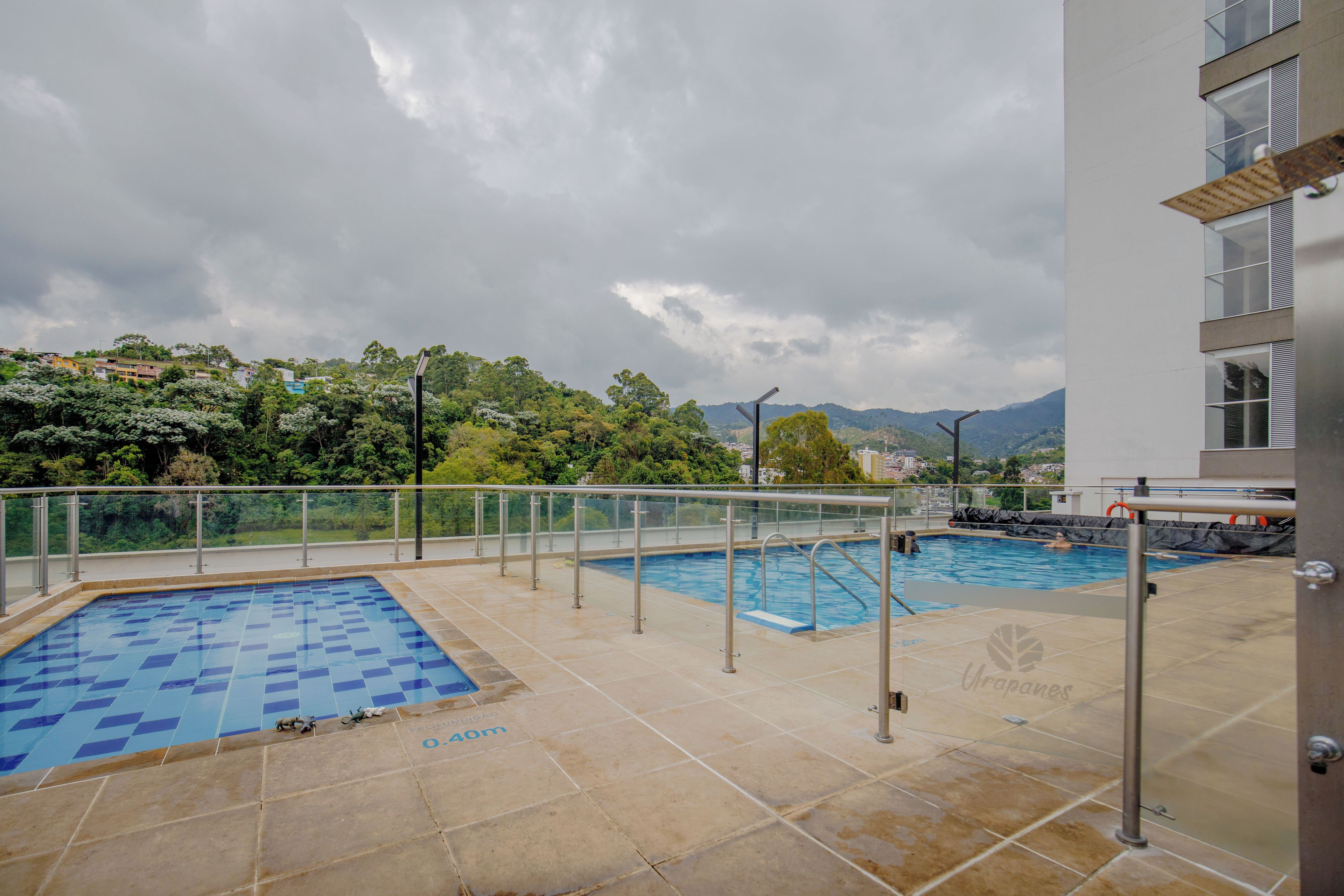 Una piscina en la azotea con vistas a un paisaje urbano y montañas al fondo.