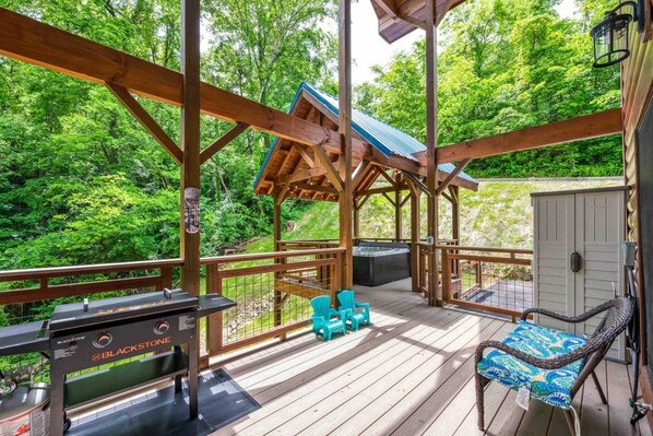 A wooden deck with a grill, chairs, and a hot tub. - Happy Days- Theater/Jukebox/Hot tub/ 2 king suites, Sleeps 10 (Sevierville)