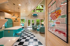 Ein Interieur einer Hütte mit Küche, Essbereich und einer Pinnwand, die lokale Sehenswürdigkeiten bewirbt.