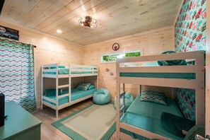 Ein Zimmer mit Etagenbetten, einer Holzzahlendecke, einer Uhr und einem gemusterten Vorhang.
