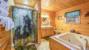Een houten badkamer met een bad, een wastafel, een toilet en een douchegordijn met een berendesign.