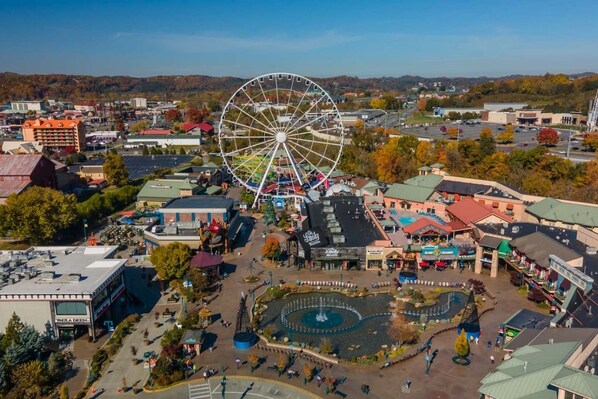 A town with a large Ferris wheel, a central fountain, and various buildings including a hotel. - Dances with Wolves- Spacious Cabin, Hot tub, Swing, Large yard (Sevierville)