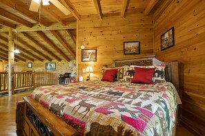Un dormitori de cabana de fusta amb un llit gran, un escriptori i una cadira.