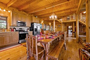 A wooden cabin interior with a kitchen, dining area, and staircase. - Dances with Wolves- Spacious Cabin, Hot tub, Swing, Large yard (Sevierville)
