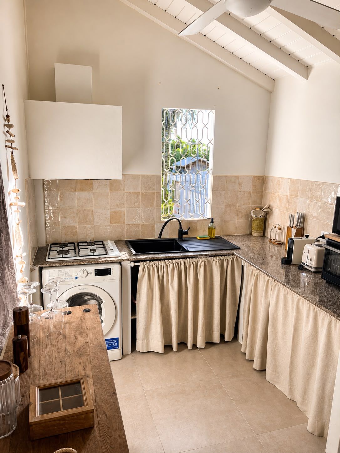 Una cocina compacta con estufa a gas, lavadora y ventana con vistas.