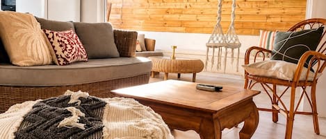 A modern living room with a sofa, chairs, a coffee table, and a hanging light fixture.