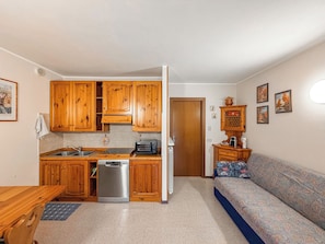 A compact kitchen with wooden cabinets, a built-in dishwasher, and a small dining table.