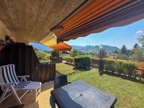 Een terras met buitenmeubilair, uitzicht op een berglandschap en een houten schutting.
