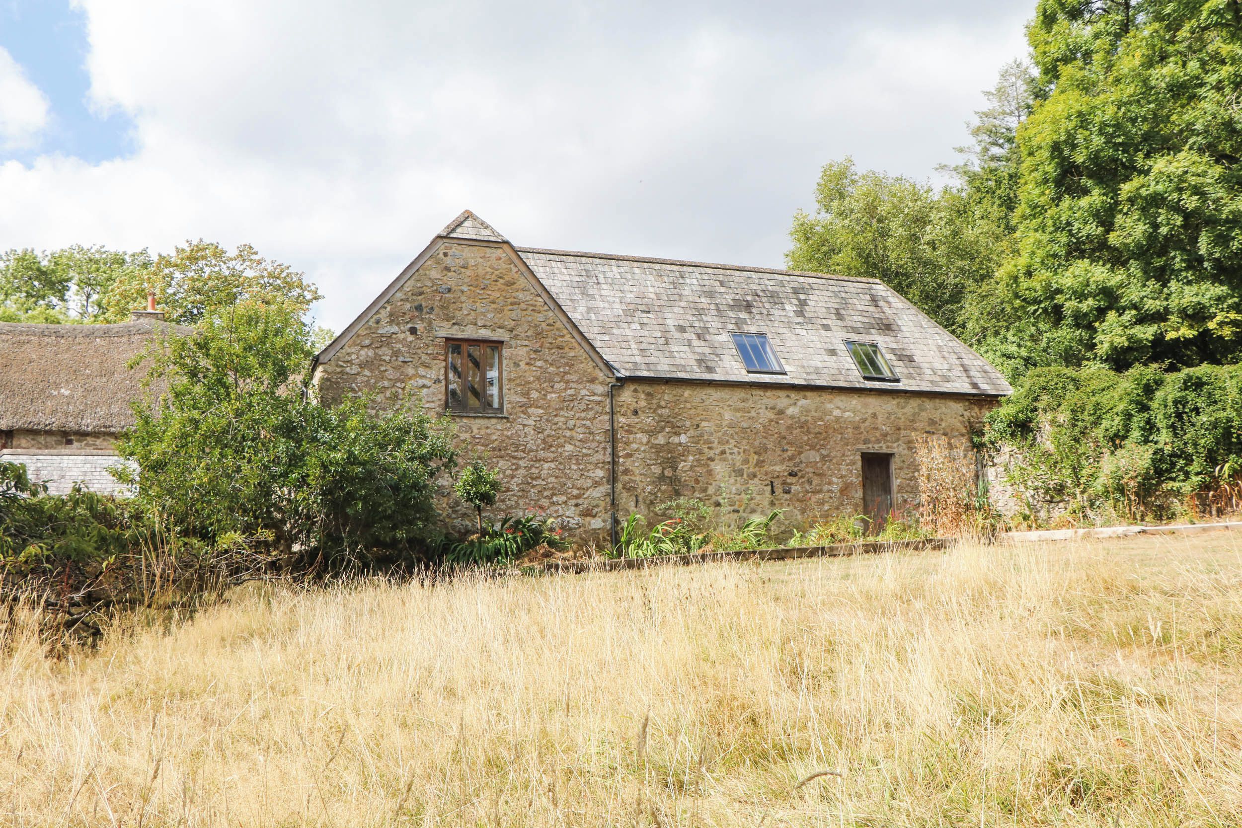 A stone building with a sloped roof, a small window, and a door.