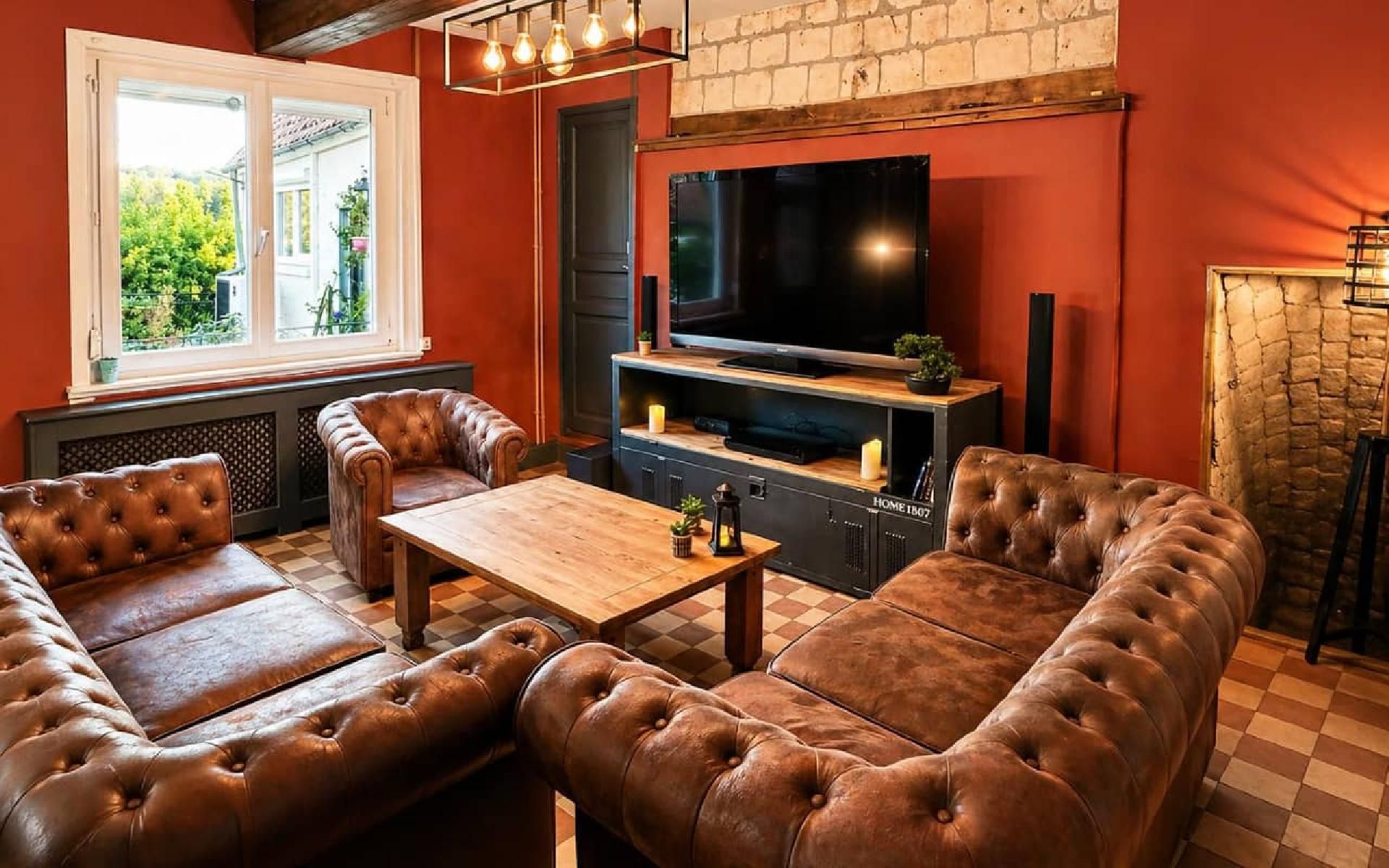 A cozy living room with leather sofas, a wooden coffee table, a flat-screen TV, and a fireplace.