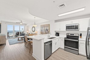 A modern kitchen with white cabinetry, stainless steel appliances, and a large island with seating. - Walk to the Beach • Resort Pools • Pier Park (Panama City Beach)