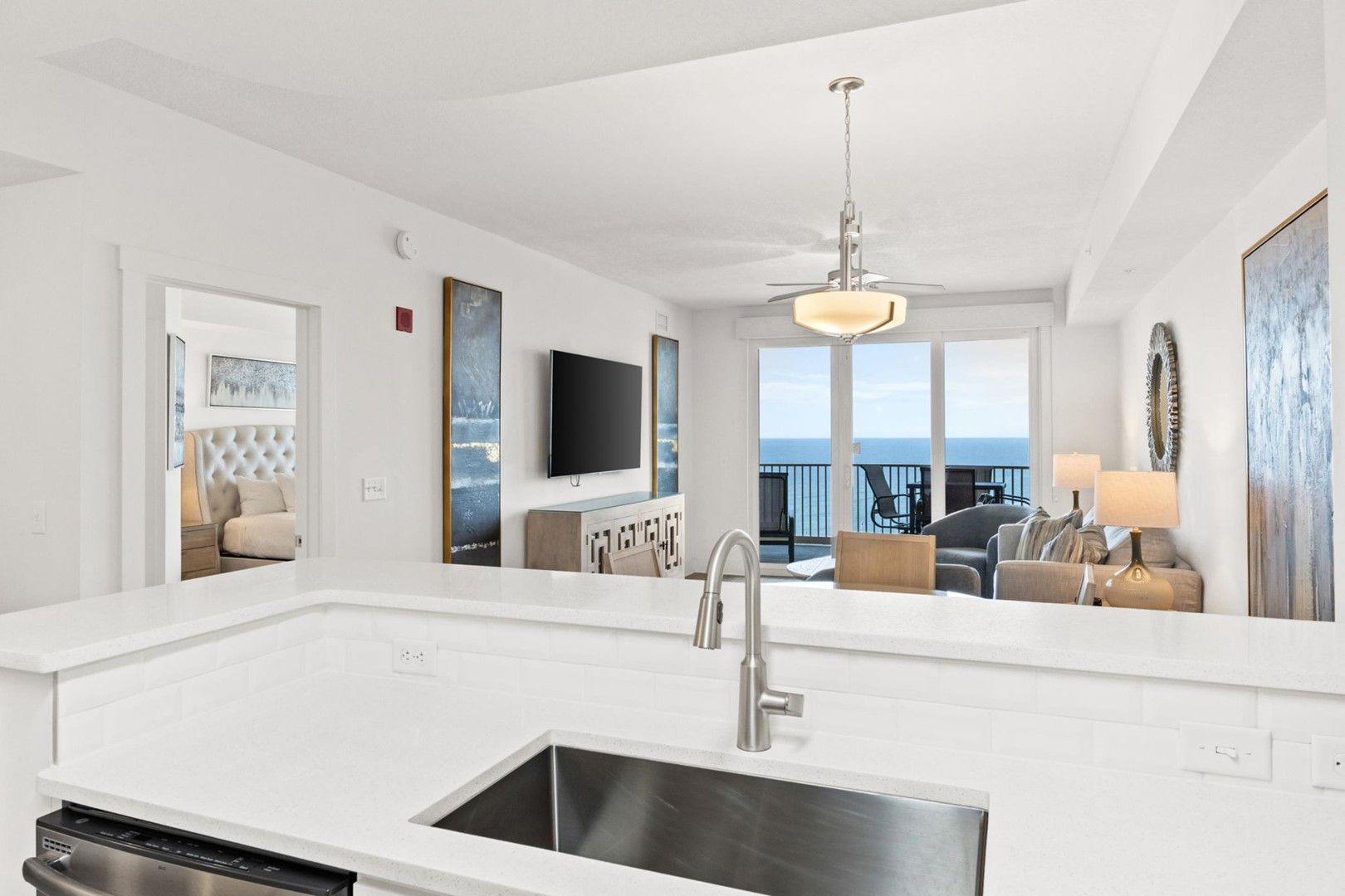 A modern kitchen with a built-in dishwasher, a stainless steel sink, and a dining area with a view of the sea.