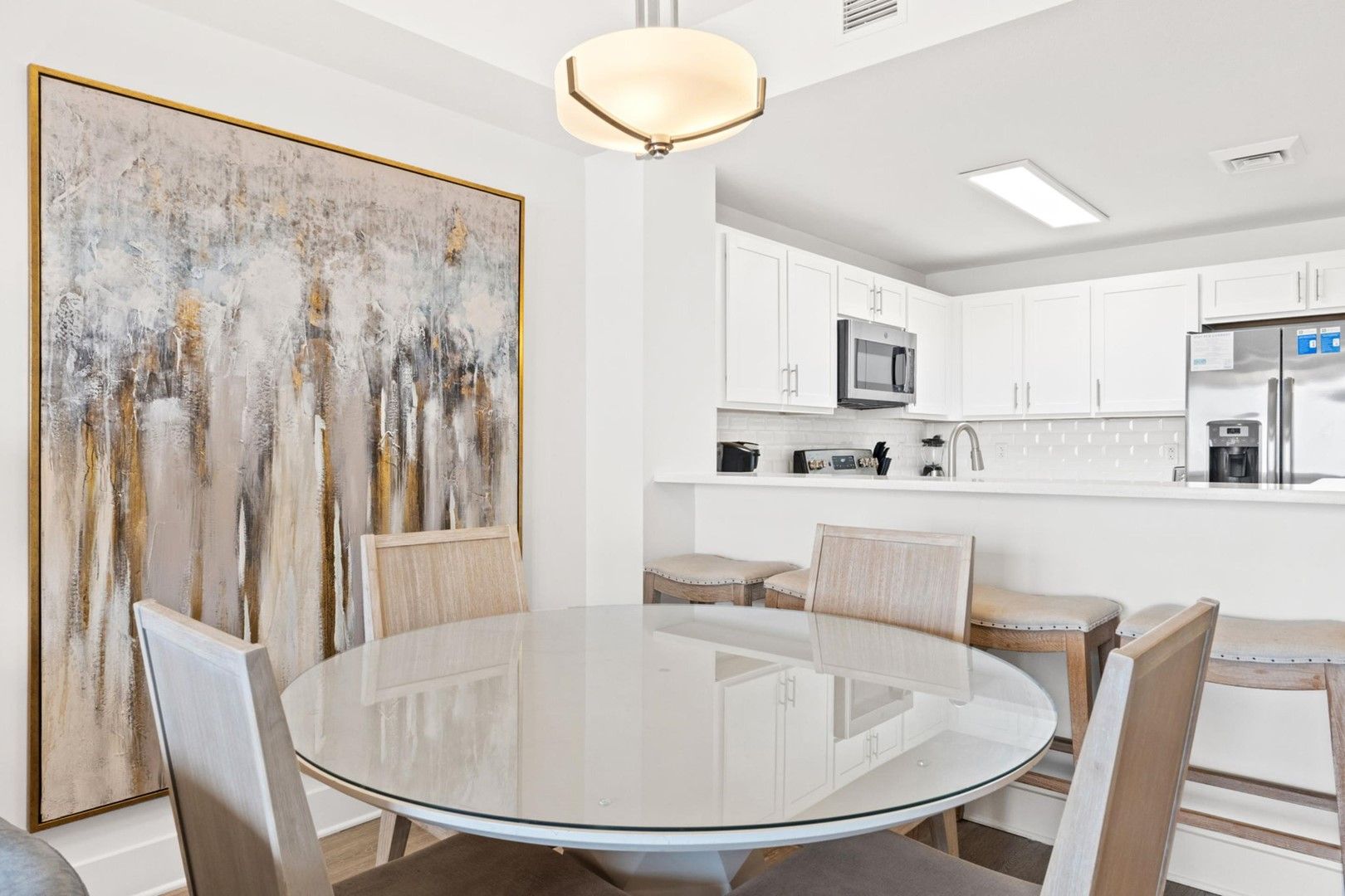 A modern kitchen with white cabinets, a stainless steel refrigerator, and a microwave.