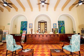 A reception area with a check-in counter, two receptionists, and a check-in desk. - Colonial Mérida Outside, Poolside Relaxation Inside | 2 Beds (Mérida)