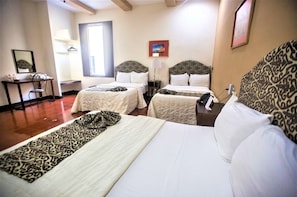 A hotel room with two beds, a desk, and a chair. There is a window providing natural light and a framed picture on the wall. - Mérida Made for Groups | 3 Double Beds + Pool (Mérida)