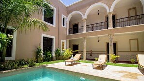 Zona de piscina amb dues gandules, una piscina nítida i un edifici amb un balcó.