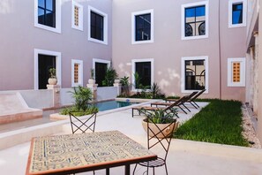A courtyard with a swimming pool, outdoor seating, and potted plants. - Explore Mérida, Then Take a Dip | Cozy Double Room (Mérida)