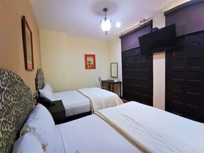 A hotel room with two beds, a small table, a chair, and a ceiling light. - Explore Mérida, Then Take a Dip | Cozy Double Room (Mérida)