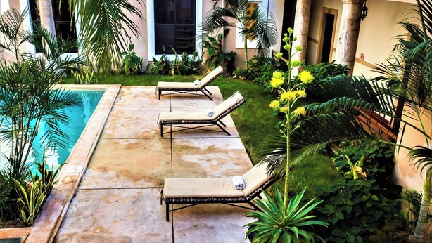 Zona de piscina amb gandules i plantes en testos.