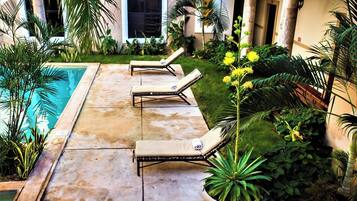 Uma área à beira da piscina com espreguiçadeiras e plantas em vasos.