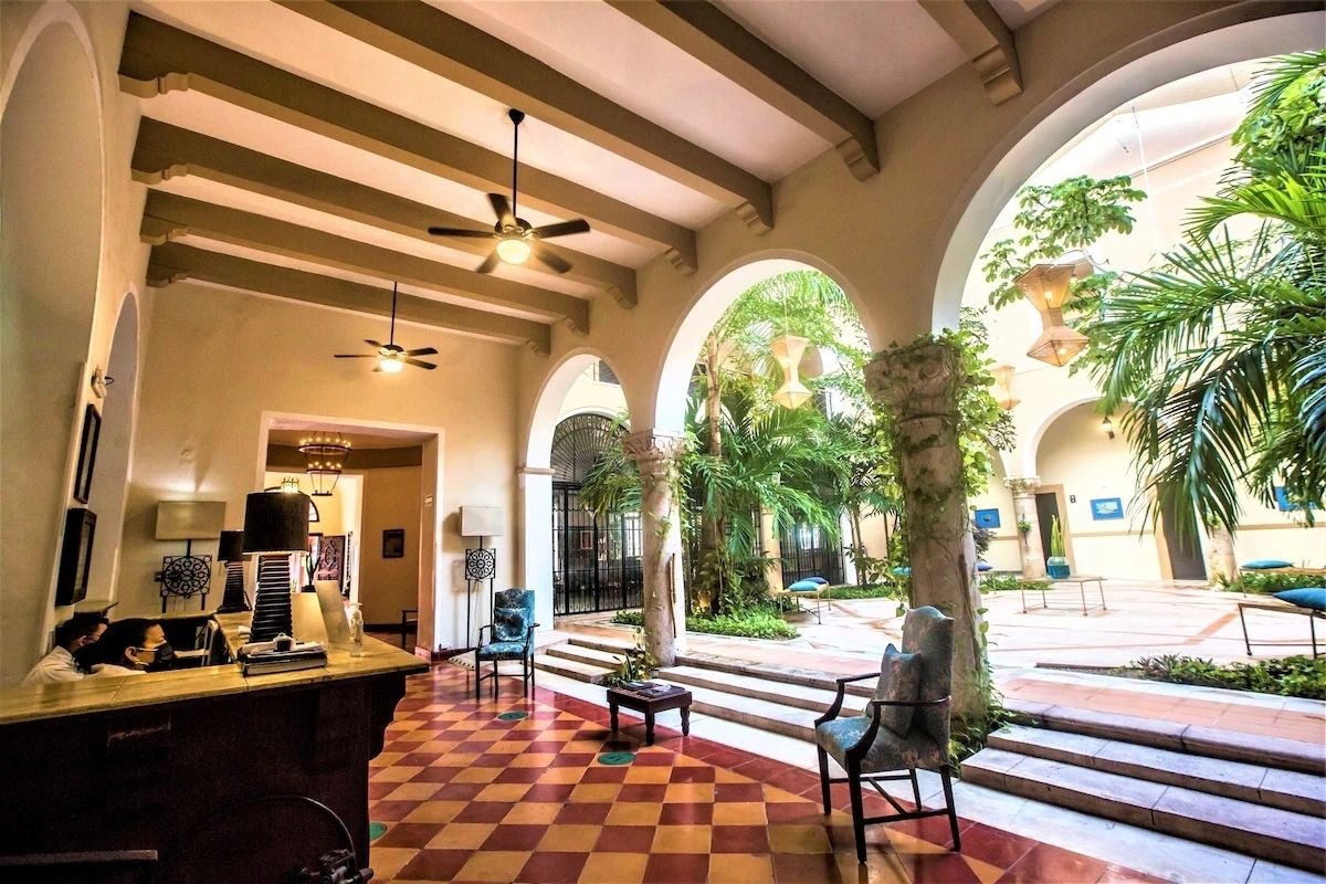 Um hall com piso xadrez, tetos em arco e uma mesa de recepção com cadeiras.